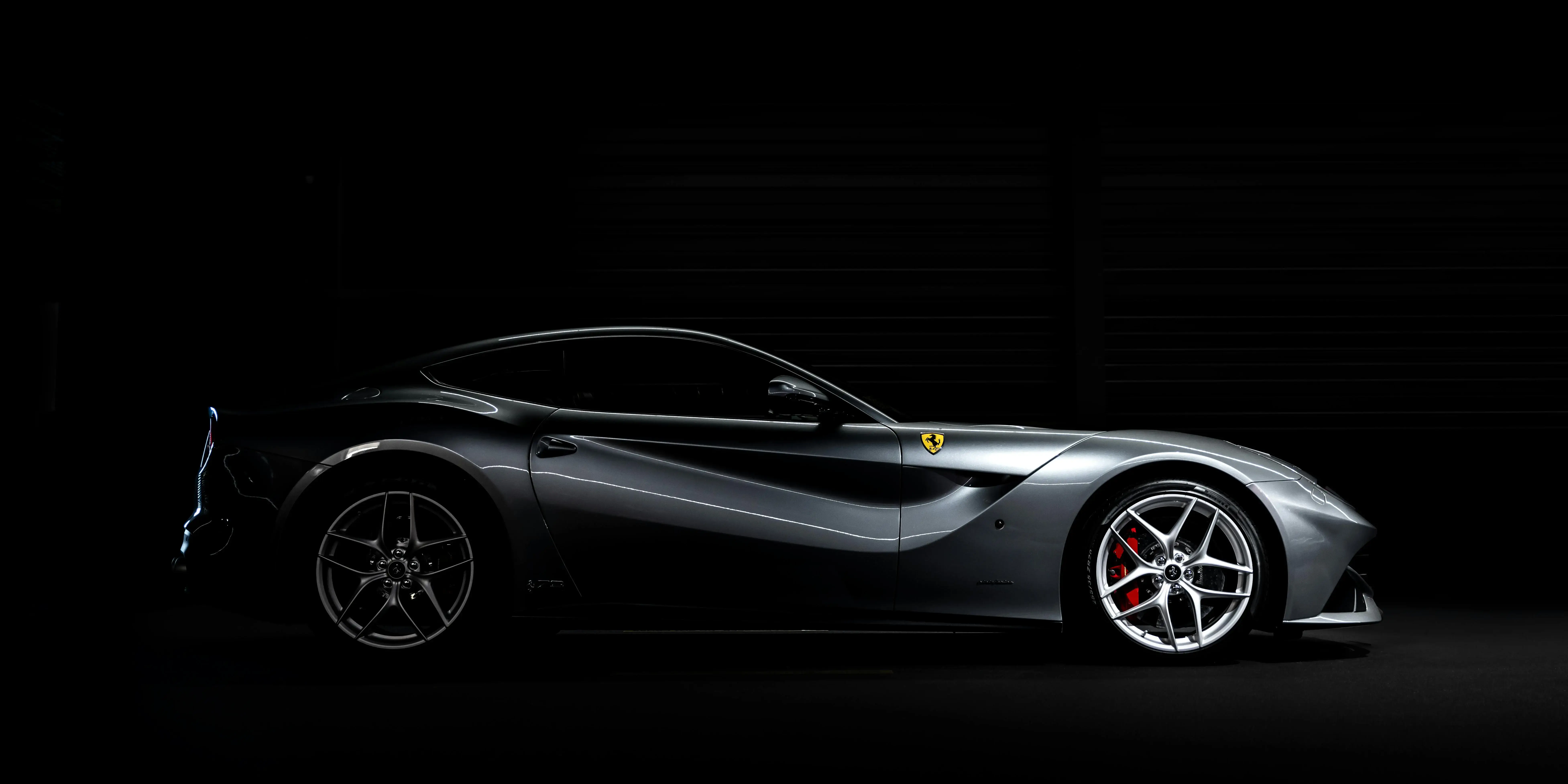 A sleek gray sports car is shown on a dark background.