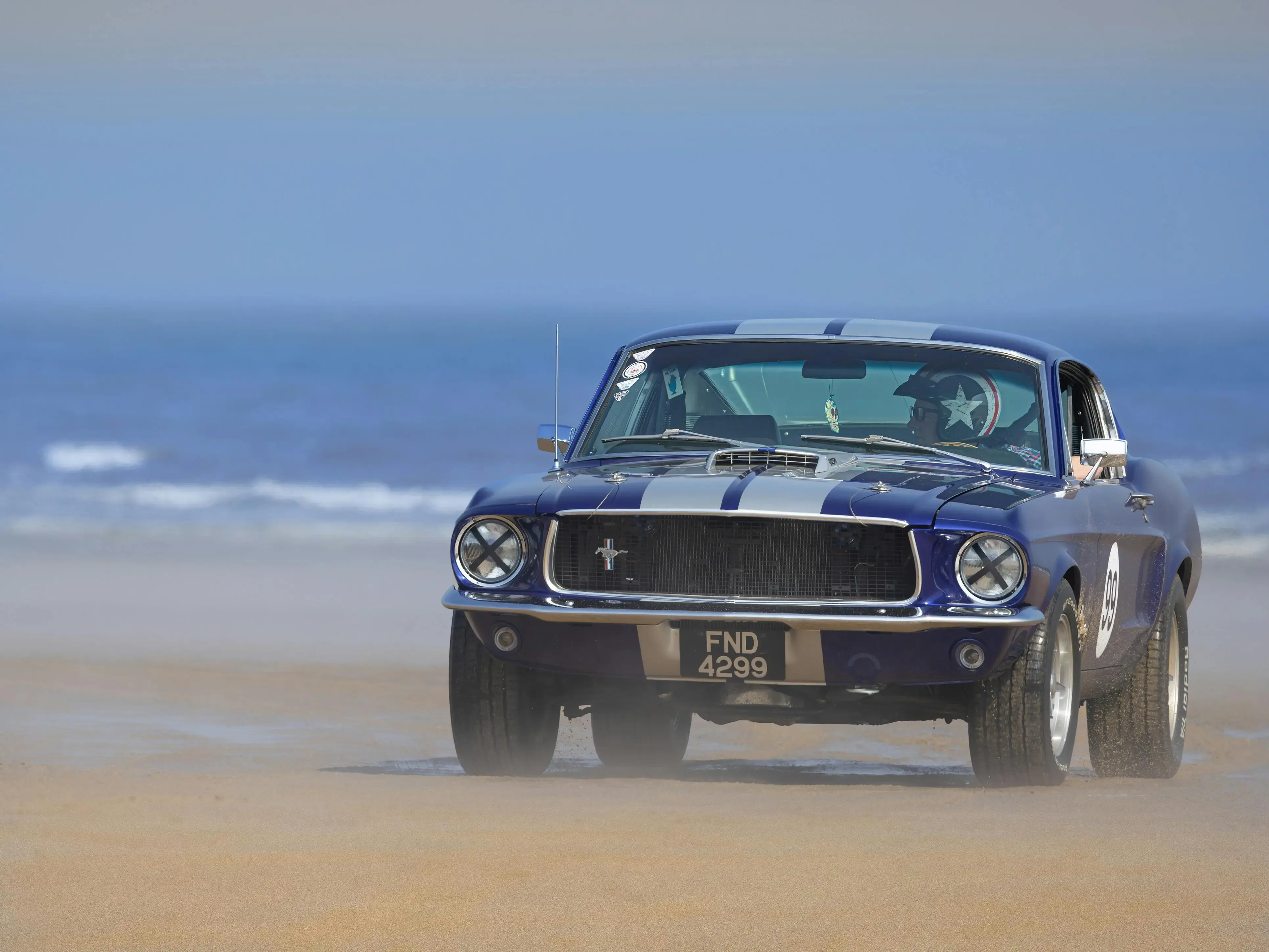Driver in a Helmet Driving a Shelby Mustang on the Beach