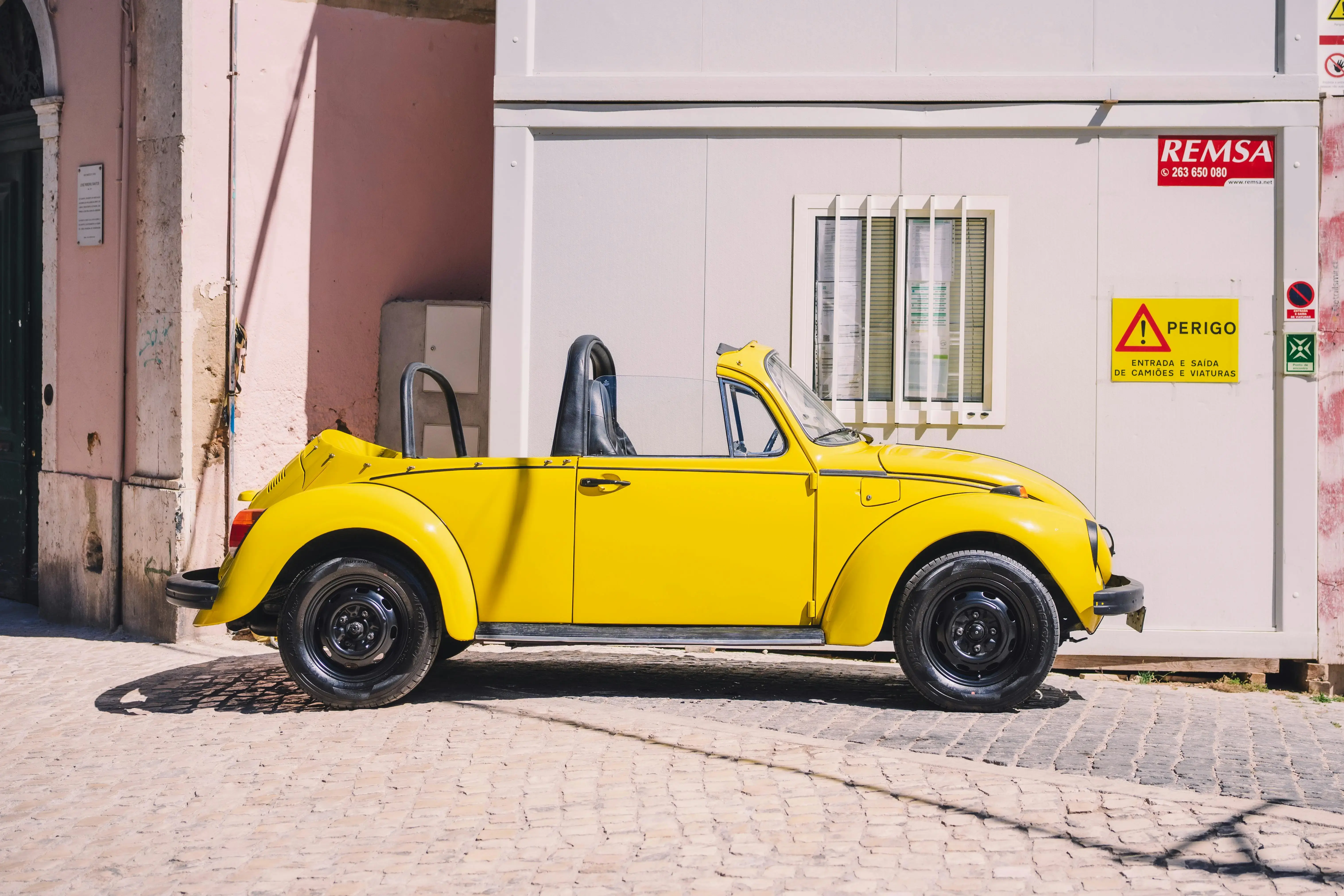 A yellow vw beetle parked in front of a building